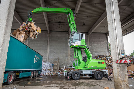 Umschlagbagger Umschlagmaschine SENNEBOGEN 825 in der Abfalllogistik, Wertstoffaufbereitung und im Recycling LKW beladen Beladung LKW mit hochfahrbarer Kabine und Mehrschalengreifer